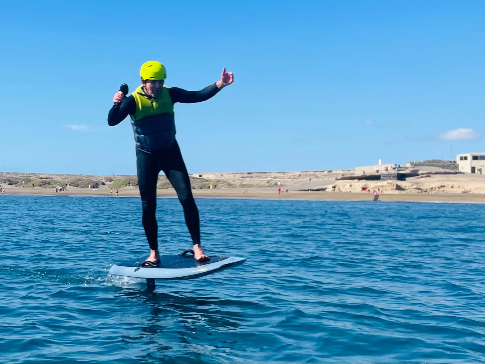 eFoil Rider gibt Daumen hoch beim Fliegen über das Wasser
